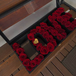 Red roses arranged in a black gift box to form letters.