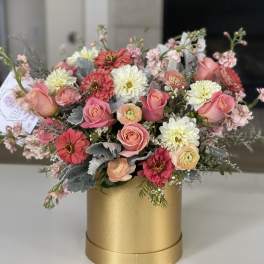 Pink and white mixed flowers arranged in a gold cylindrical box