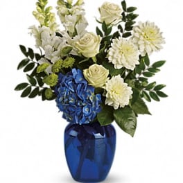 White and blue floral arrangement in a cobalt vase