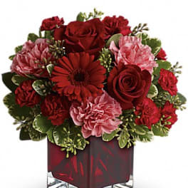Red and pink flower arrangement in a square glass vase