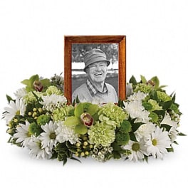 White and green floral tribute surrounding a framed photo