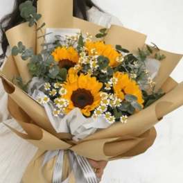 Bouquet of sunflowers and small white daisies wrapped in brown paper