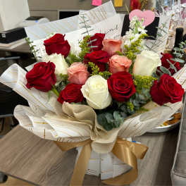 Bouquet of red, white, and blush roses wrapped in patterned paper