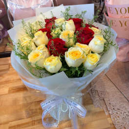 Bouquet of red and cream roses wrapped in white paper