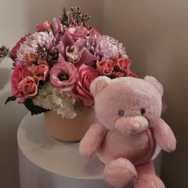 Pink flower arrangement in a round box with a pink teddy bear