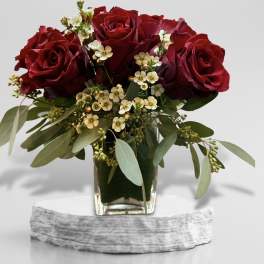 Red roses in a glass vase with small white filler flowers