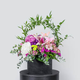 Mixed floral arrangement in a black box with pink, white, and purple blooms