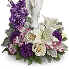 Purple and white floral arrangement with an angel figurine
