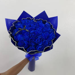Bouquet of vivid blue roses wrapped in blue paper with a ribbon