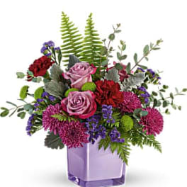Purple and pink flower arrangement in a lavender glass vase