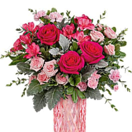 Pink roses and carnations arranged in a pink glass vase
