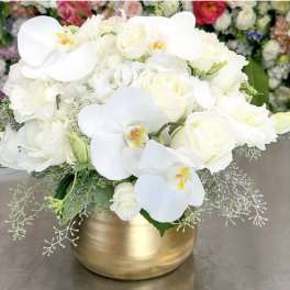 White roses and orchids arranged in a gold vase