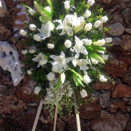 White floral standing spray with lilies and roses on an easel