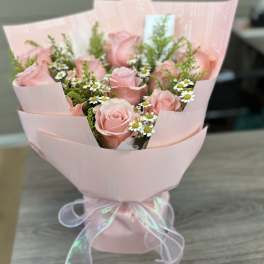 Pink rose bouquet with small white daisies wrapped in pale pink paper