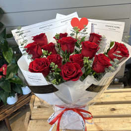 Bouquet of red roses wrapped in white paper with a red ribbon