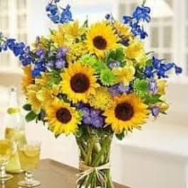 Bouquet of sunflowers and blue flowers in a glass vase