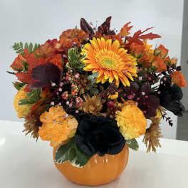 Autumn floral arrangement in an orange pumpkin vase with orange and yellow blooms