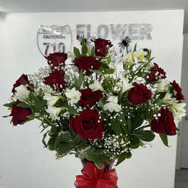 Red roses and white alstroemeria in a vase with a red ribbon