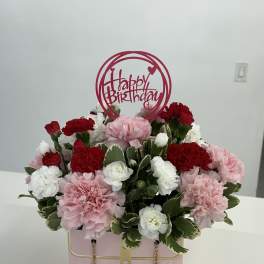 Pink and red carnations in a pink gift box with a Happy Birthday topper