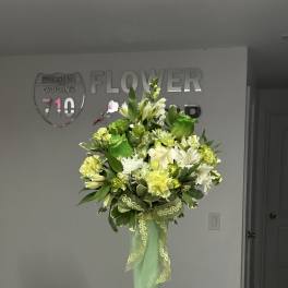 Tall green vase holding a white and green floral arrangement