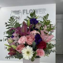 Mixed bouquet of pink, purple, and white flowers in a pale pink vase