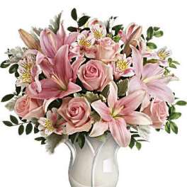 Pink lilies and roses arranged in a white vase