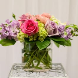 Pink and lavender roses with purple flowers in a glass vase