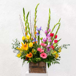 Tall mixed bouquet in a wooden box with lilies, tulips, and gerbera daisies