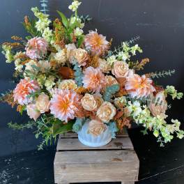 Large peach and cream floral arrangement in a white vase