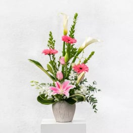 Pink gerberas and lilies arranged in a gray vase