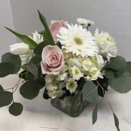 Pink roses and white flowers arranged in a clear glass vase