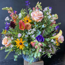 Mixed bouquet with peach roses, purple blooms, and yellow daisies in a vase