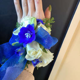 Hand corsage with white and blue flowers and a large blue ribbon
