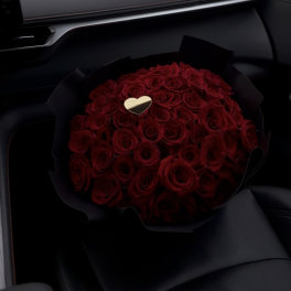 Bouquet of red roses with a small gold heart in black wrap