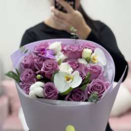 Bouquet of purple roses and white orchids wrapped in lavender paper