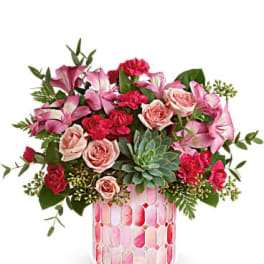 Pink and red floral arrangement in a patterned glass vase