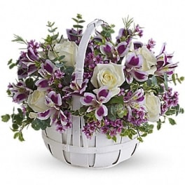 Basket of white roses and purple orchids with greenery