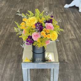 Bright bouquet of yellow, pink, and purple roses in a black box