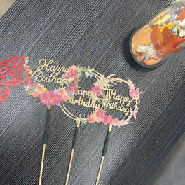 Birthday cake toppers with floral decorations and gold lettering