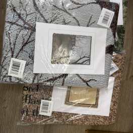 Stack of packaged woven decorative textiles with printed scene inserts