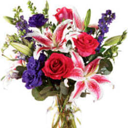 Bouquet of red roses, pink lilies, and purple flowers in a glass vase