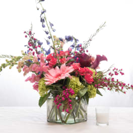Mixed pink and purple flowers arranged in a glass vase