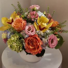 Mixed bouquet of roses, orchids, and hydrangeas in a white vase