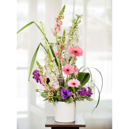 Tall mixed bouquet in a white cylindrical vase with pink and purple flowers