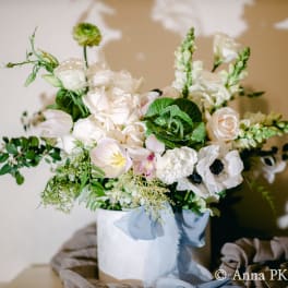 White floral arrangement in a white box with a blue ribbon