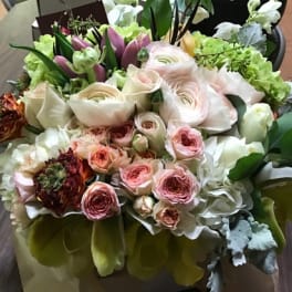 Mixed bouquet of pale pink and white flowers in a wrapped arrangement