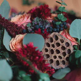 Bouquet of pink roses and burgundy flowers with eucalyptus and a dried seed pod