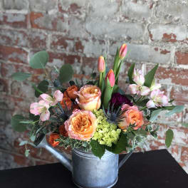 Mixed bouquet in a metal watering can with peach roses and pink tulips
