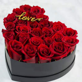 Heart-shaped box of red roses with a gold "love" topper