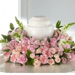 Pink roses and carnations arranged around a white urn